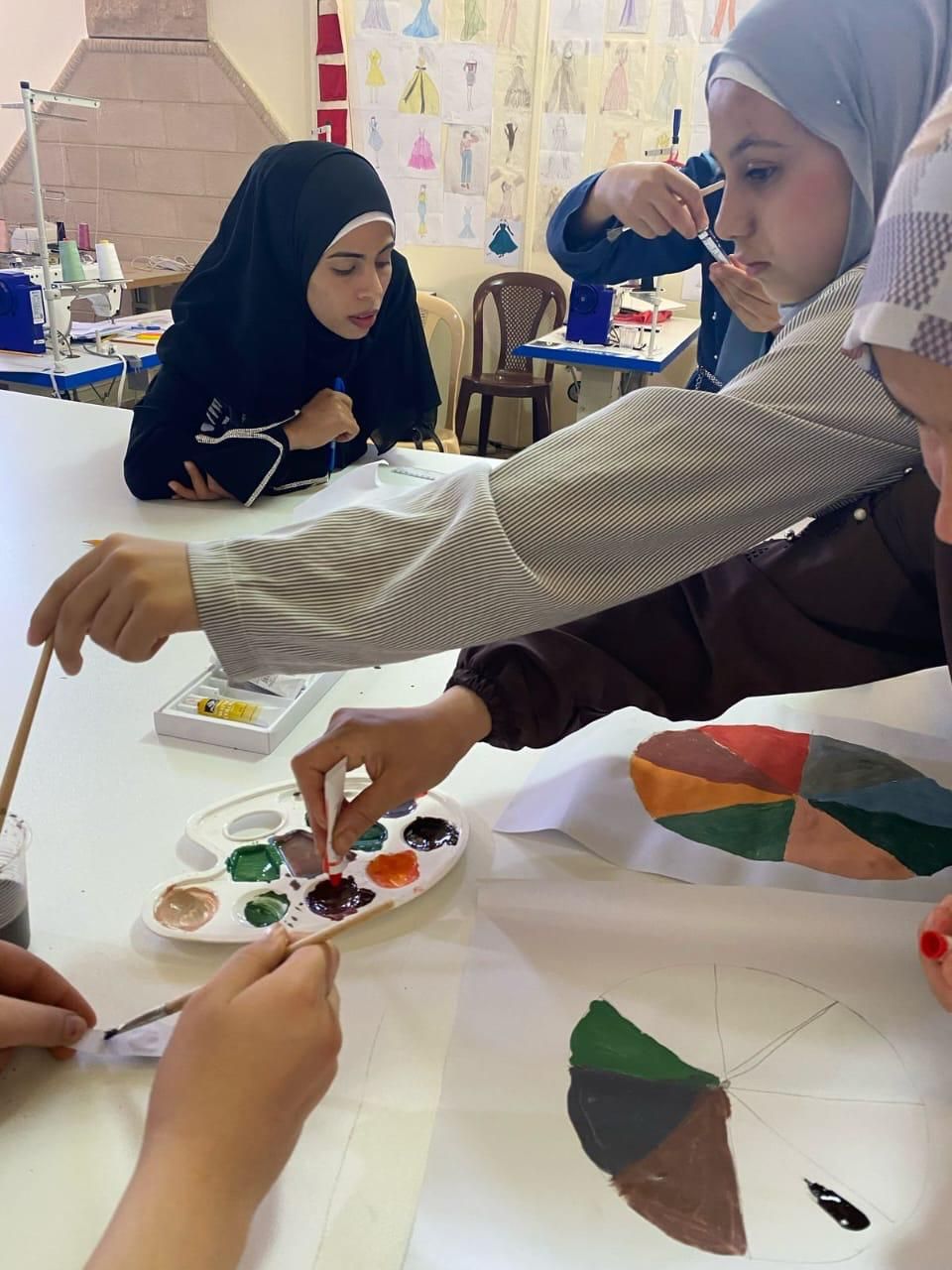 متدرّبات يلوّنّ دائرة الألوان بالألوان المائية خلال التدريب على التصميم
